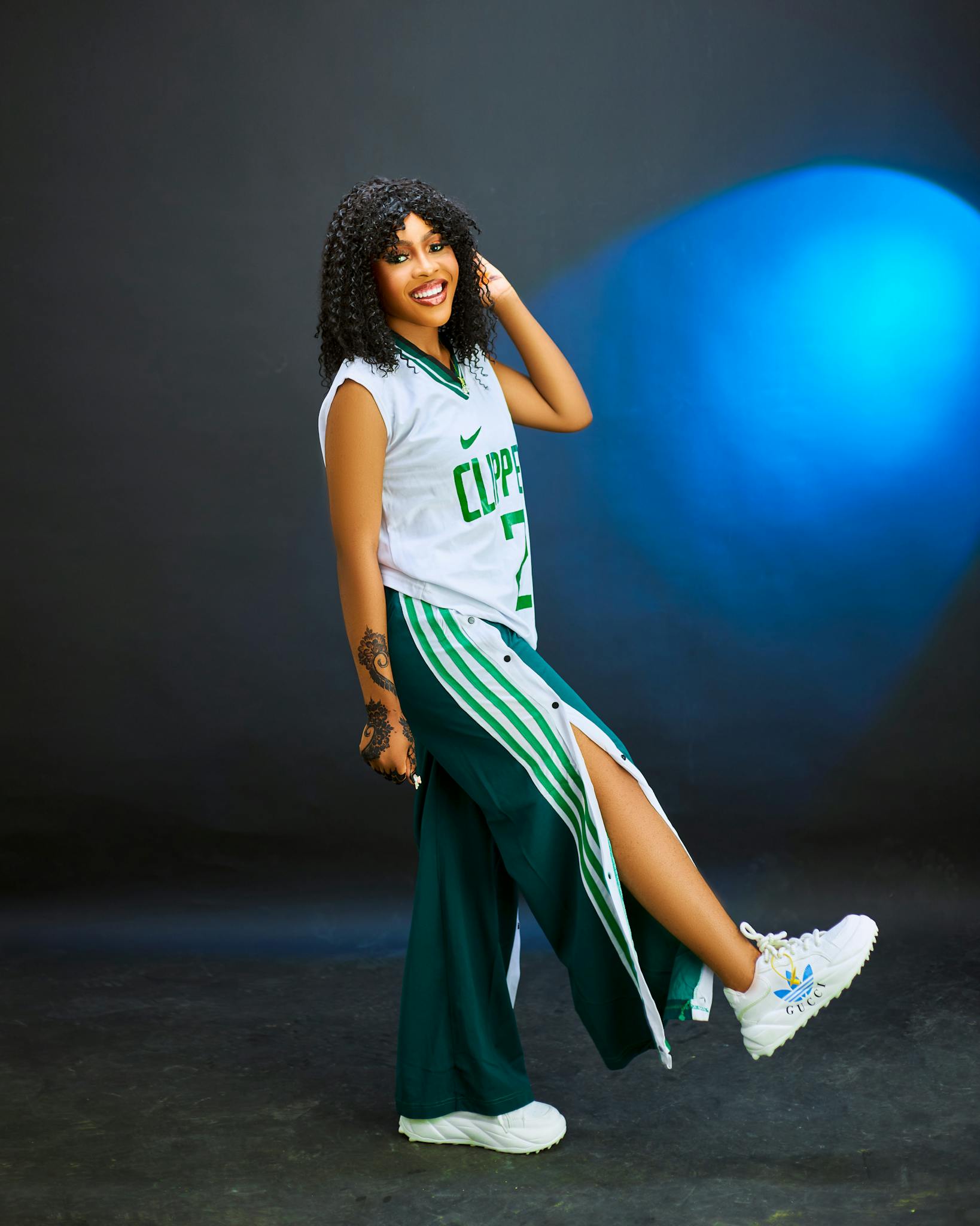 Smiling young woman in stylish basketball-inspired fashion posing in studio.