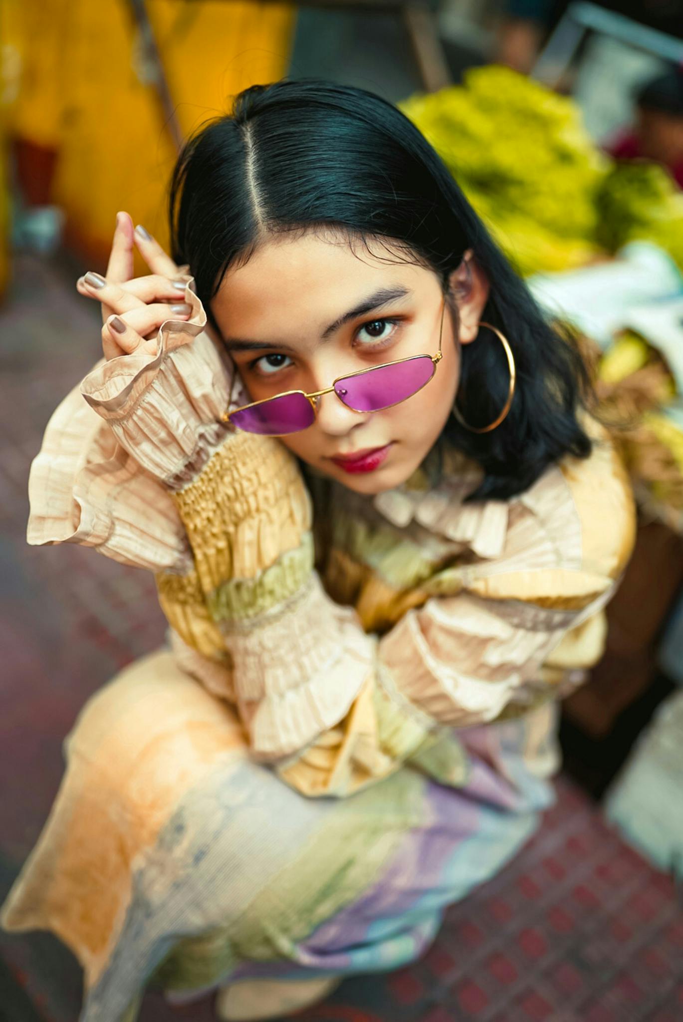 Trendy female in colorful attire and tinted sunglasses posing confidently outdoors.